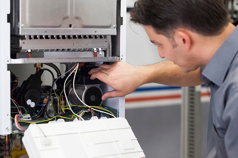 4 Important Heat Pump Maintenance Tips. A technician doing repairs.